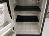 a small black and white refrigerator with its door open