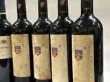 six bottles of wine are lined up in a row on a white surface