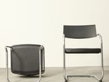 pair of black and chrome chairs in a room with a white wall