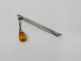 an orange glass bead hangs from a metal hook on a white surface
