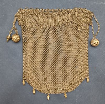 un sac à main en maille dorée, orné de clochettes qui pendent de tous côtés
