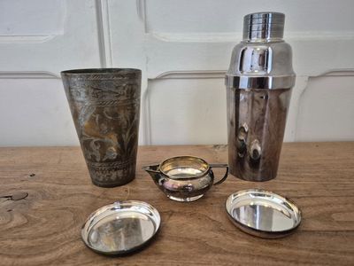 a lot of silver items on a table next to a shaker