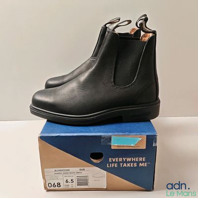 Les bottines Chelsea en cuir noir sont posées sur une boîte en carton