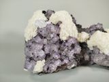 purple and white crystals on a white surface with a gray background