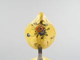 a yellow vase with a flower on it on a stand