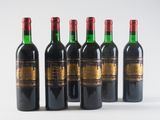 six bottles of wine are lined up on a white surface