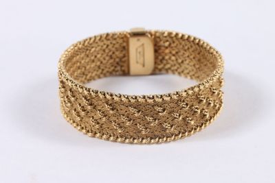 gros plan d'un bracelet en or sur fond blanc