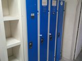 two blue lockers in a bathroom next to a white shelf
