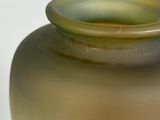a green and yellow vase sitting on a white surface