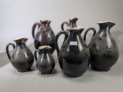 cinq vases noirs posés les uns à côté des autres sur une table