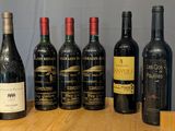 several bottles of wine are lined up on a wooden table