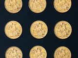 six gold sovereigns of different sizes and shapes on a black surface