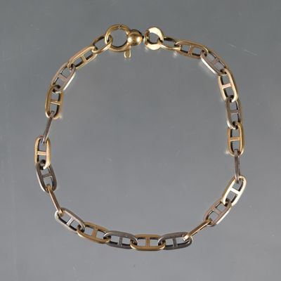 gros plan d'un bracelet en chaîne en or sur une surface grise