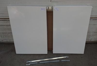 pair of white refrigerators sitting in front of a garage door