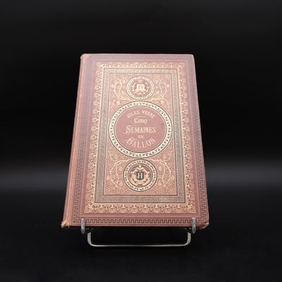 un vieux livre posé sur un support métallique, lui-même posé sur une surface noire