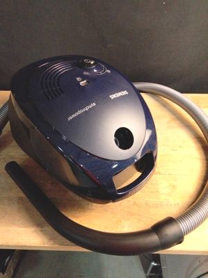 un aspirateur posé sur une table, muni d'un tuyau