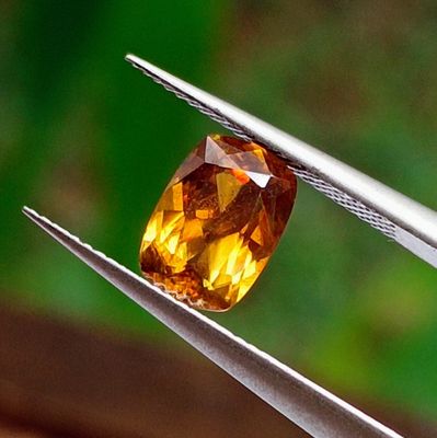 a close up of a yellow diamond being held by a pair of pliers