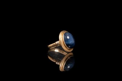 gros plan d'une bague en or avec une pierre bleue