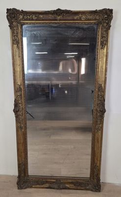 un miroir au cadre doré ouvragé dans une pièce dotée d'un parquet