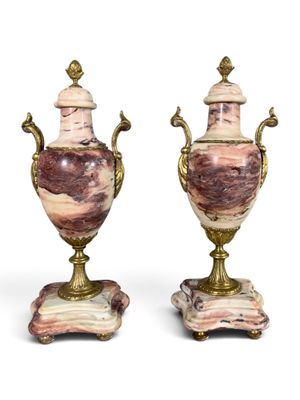 une paire de vases roses et dorés posés sur des socles en marbre, sur fond blanc
