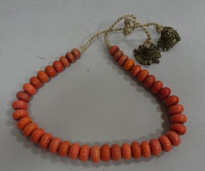 a close up of an orange beaded necklace on a white surface