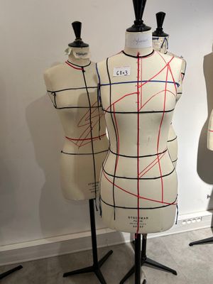 three mannequins with red lines on them in a room