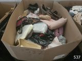 une boîte en carton remplie de vêtements et de chaussures posée par terre