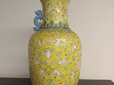 un vase jaune posé sur une table, orné d'un oiseau bleu