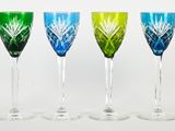 six verres à vin de couleurs différentes alignés sur une surface blanche