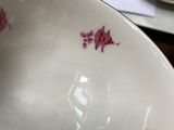 a white bowl with pink flowers on it sitting on a table