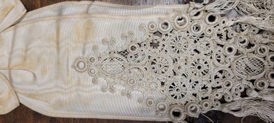 une robe blanche ornée d'un nœud, posée sur un parquet