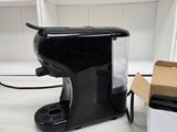 a black coffee maker sitting next to a box on the floor