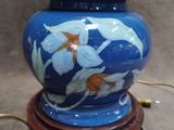 a blue vase with white flowers on it on a wooden stand