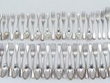 a lot of forks and spoons laid out on the table