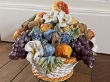 un vase posé par terre, contenant un bouquet de fruits