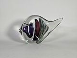 un gros plan d'une sculpture de poisson en verre posée sur une surface blanche