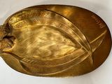 une plaque dorée ornée d'une feuille sur un fond blanc