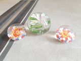 trois vases en verre posés sur une table, contenant des fleurs
