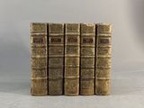 six vieux livres empilés les uns sur les autres sur une surface blanche