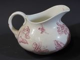 a white pitcher with a pink floral design on it