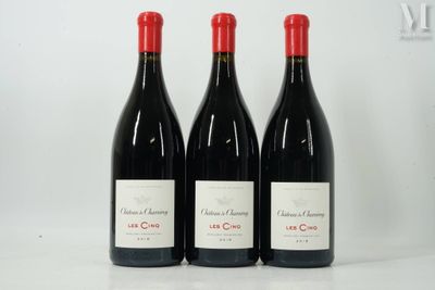 trois bouteilles de vin rouge sont alignées sur une surface blanche