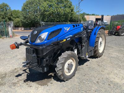 un tracteur bleu garé sur un parking en gravier