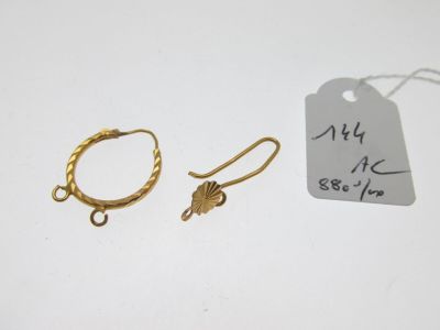deux boucles d'oreilles en or et une étiquette sur un fond blanc