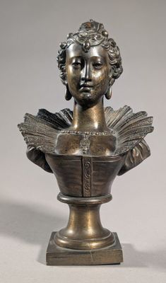 bronze bust of a woman holding a book on a pedestal