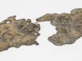 deux pièces en bronze sur une surface blanche avec un fond blanc