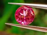 un gros plan d'un diamant rose tenu par une paire de pinces