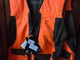 an orange vest is hanging on a wooden wall in a room