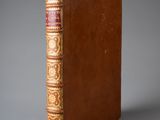 un livre marron aux bords dorés et à la reliure rouge