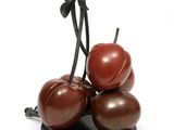 three cherries sitting on top of each other on a black plate