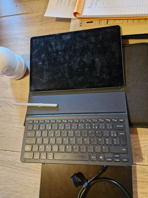 un ordinateur portable posé sur un bureau, à côté d'un cahier